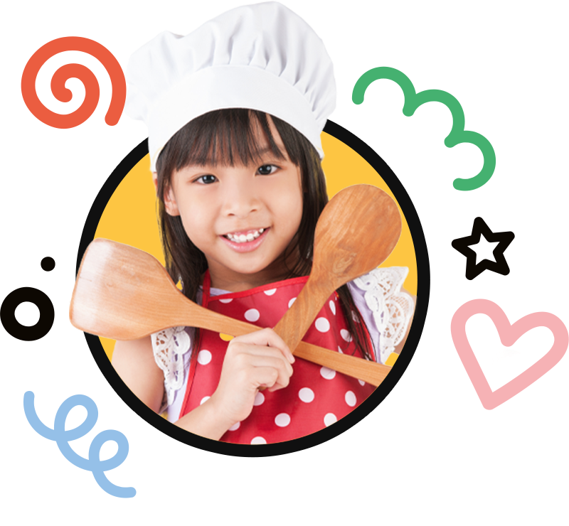 A little girl wearing a chef hat is holding two wooden spoons