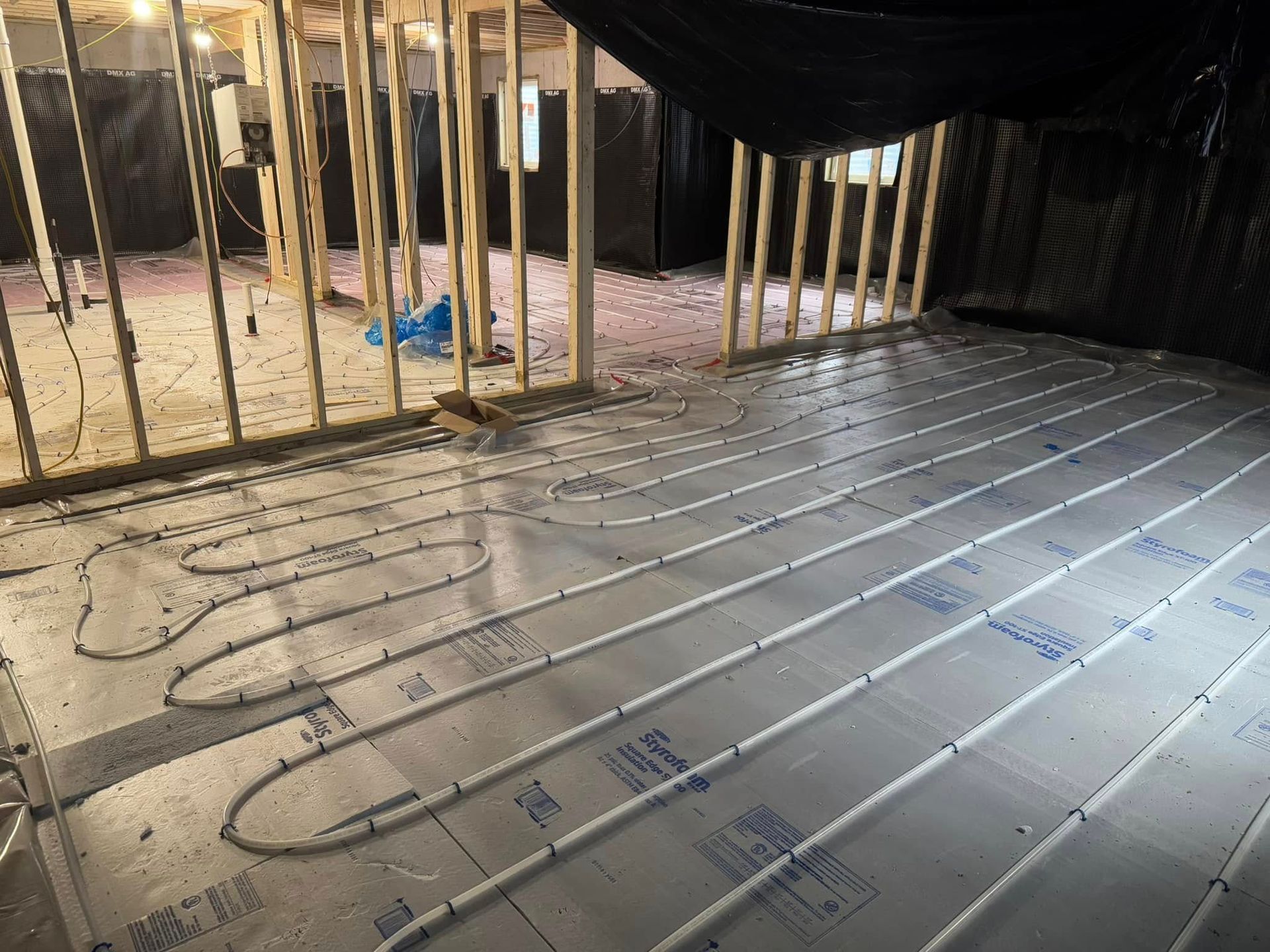 A room under construction with a lot of pipes on the floor.
