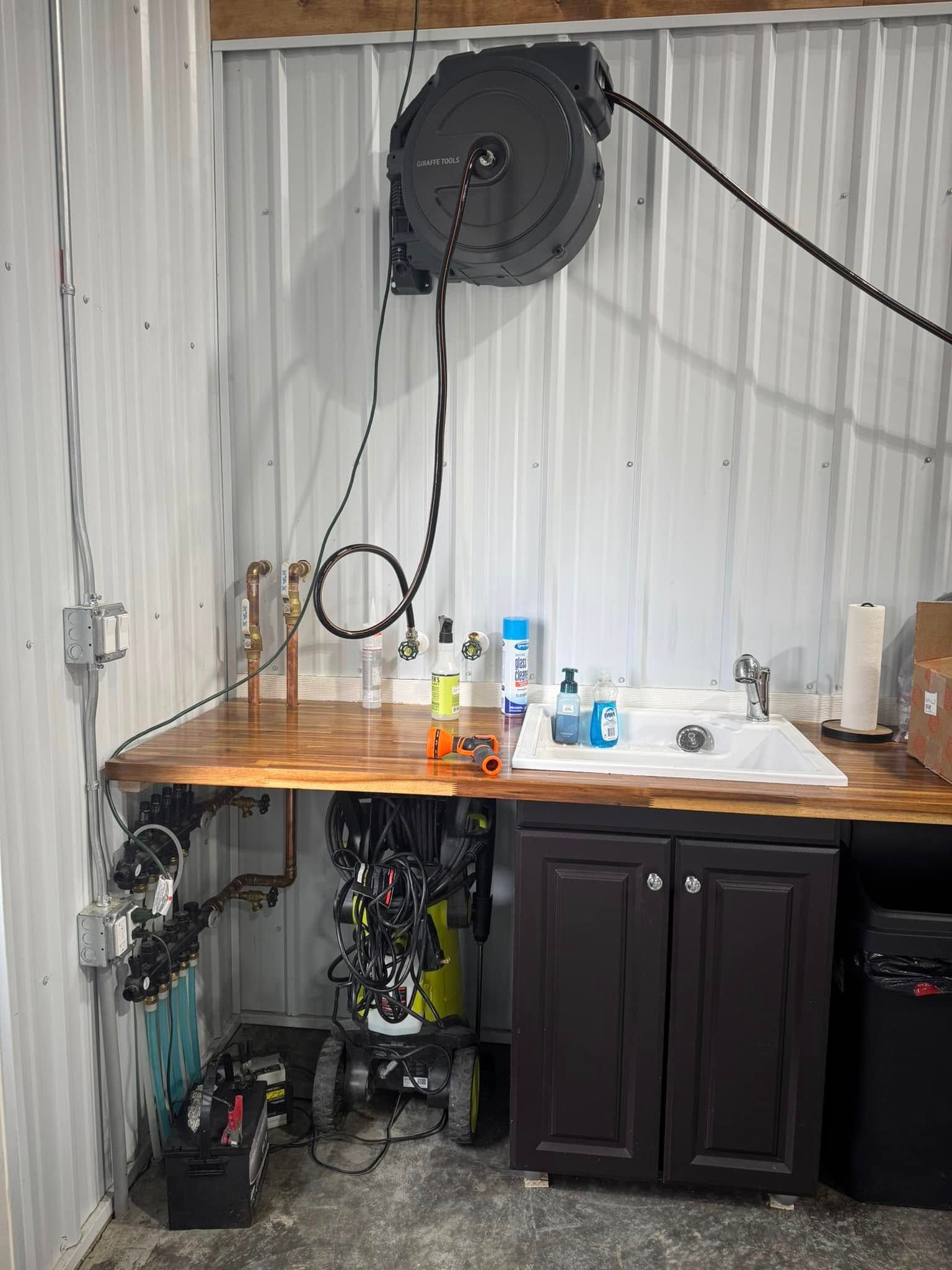 A bathroom with a sink and a hose reel on the wall.