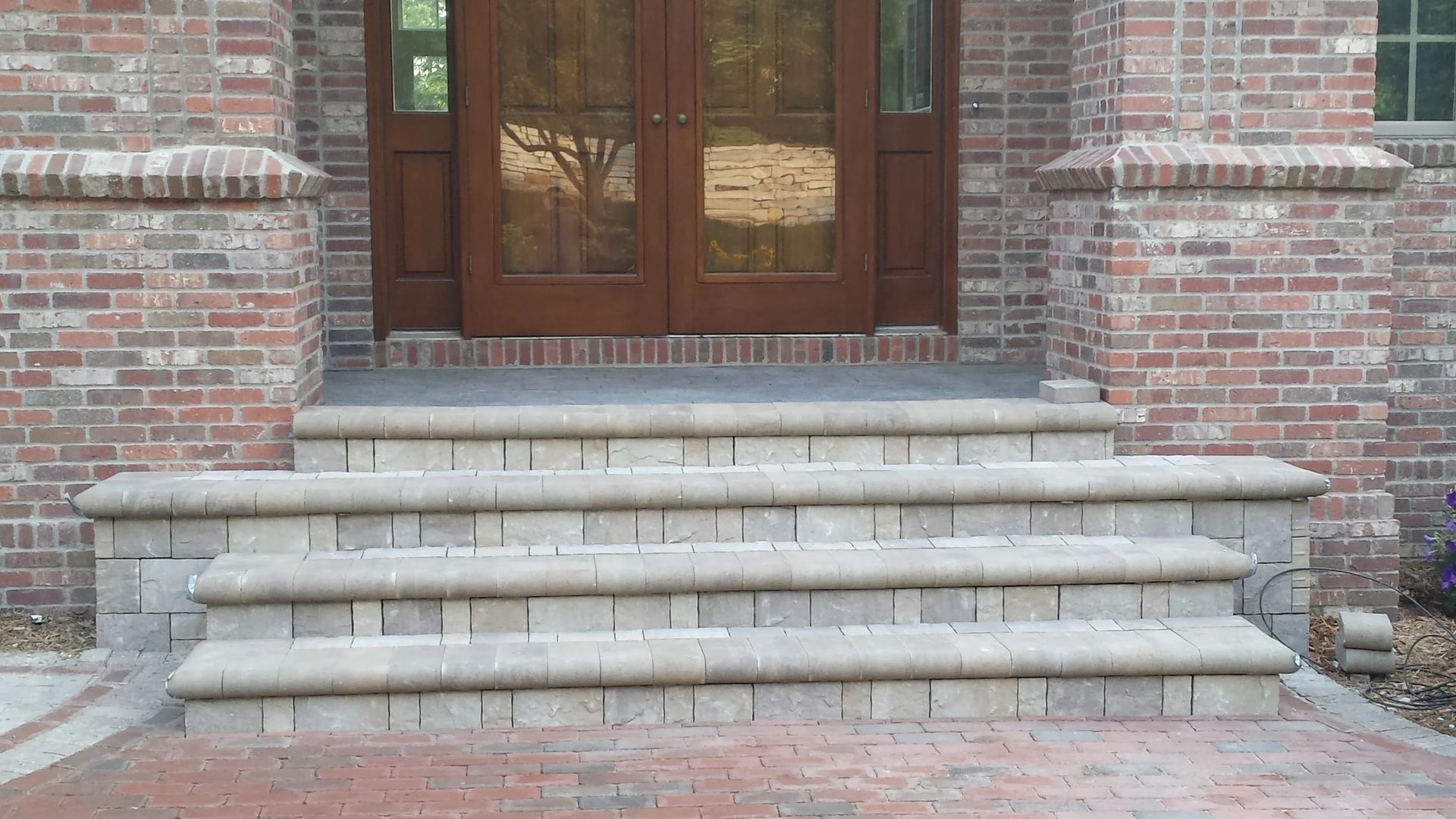 Brick building entrance with wooden double doors and wide stone steps leading up to it