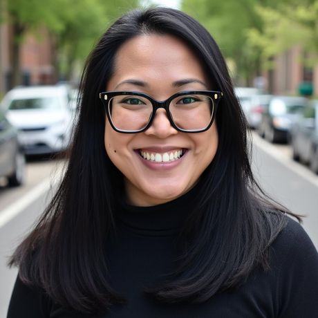 Smiling person with black glasses on a tree-lined city street