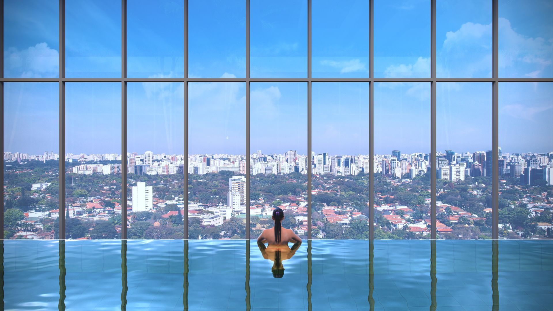 Um homem está nadando em uma piscina infinita com vista para uma cidade.