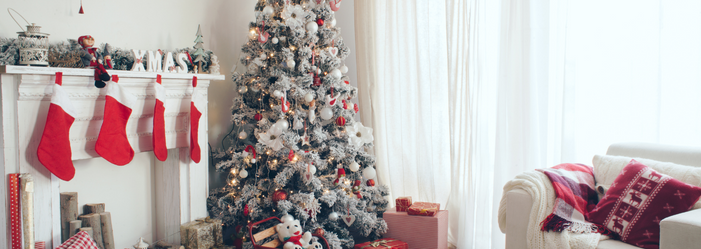 A living room decorated for christmas with a christmas tree and fireplace.