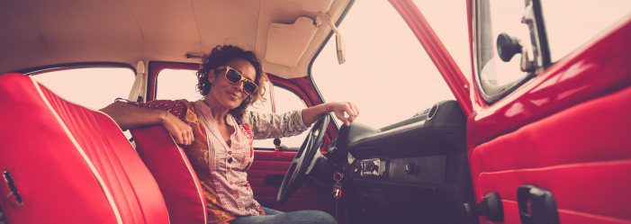 A woman is sitting in the driver 's seat of a red car.