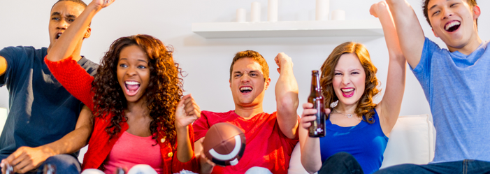 A group of people are sitting on a couch watching a football game.