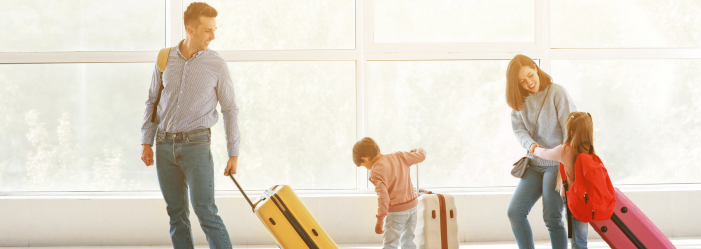 A family is traveling for the holidays pulling luggage at the airport.