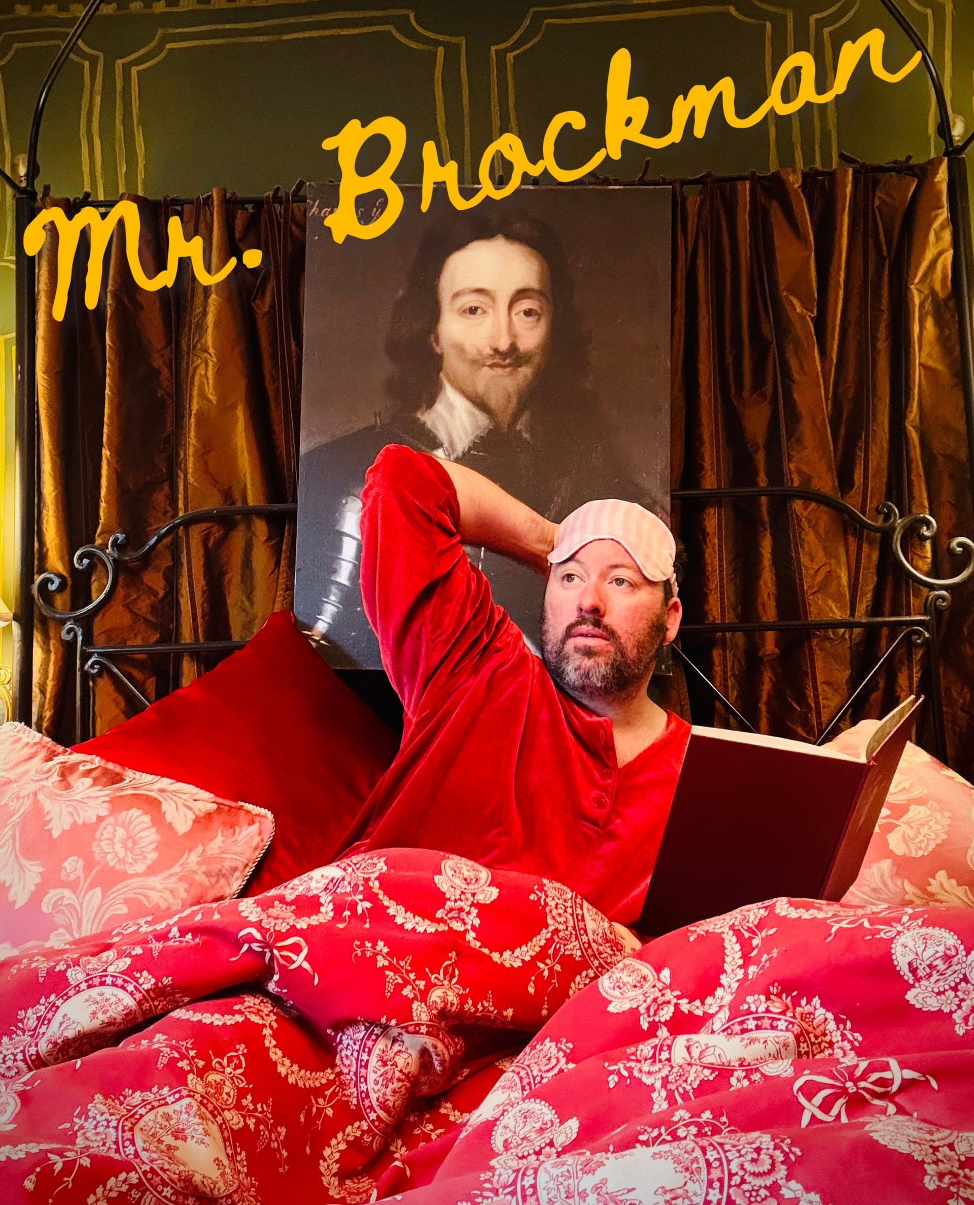 Reclining in red pajamas and a sleep mask beneath an oil portrait of Charles I.