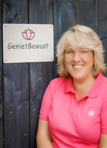 Vrouw in een roze shirt staat naast een bord met de tekst 