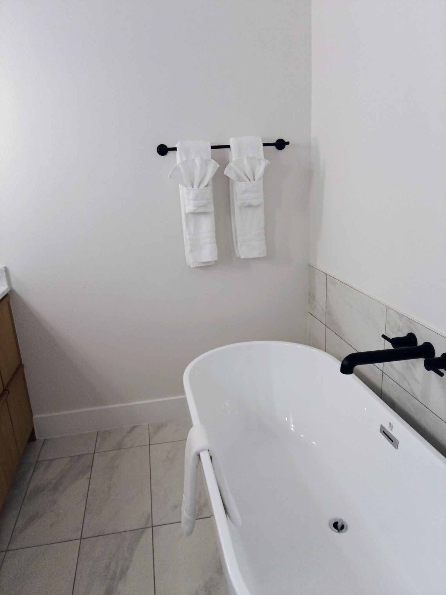 White bathtub with black faucet, towels hanging, in a bathroom.