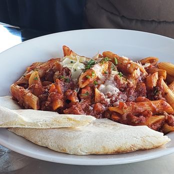 A white plate topped with pasta and a tortilla on a table