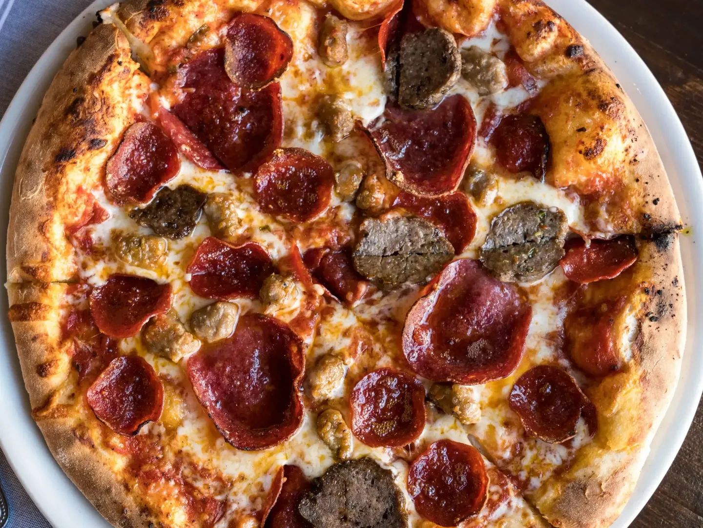 A pepperoni pizza with sausage and cheese on a white plate.