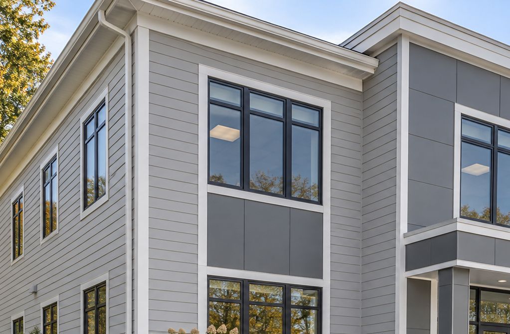 Modern gray building exterior with large windows and white trim under a clear sky