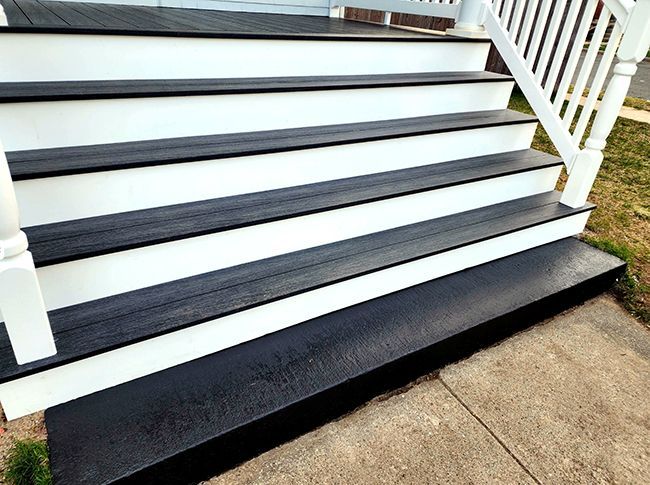 White outdoor staircase with black anti-slip treads and white railings on a porch