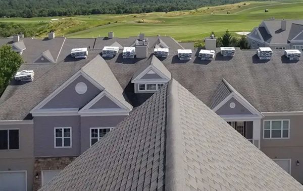 Aerial view of gray-roofed residential buildings with green fields in the background
