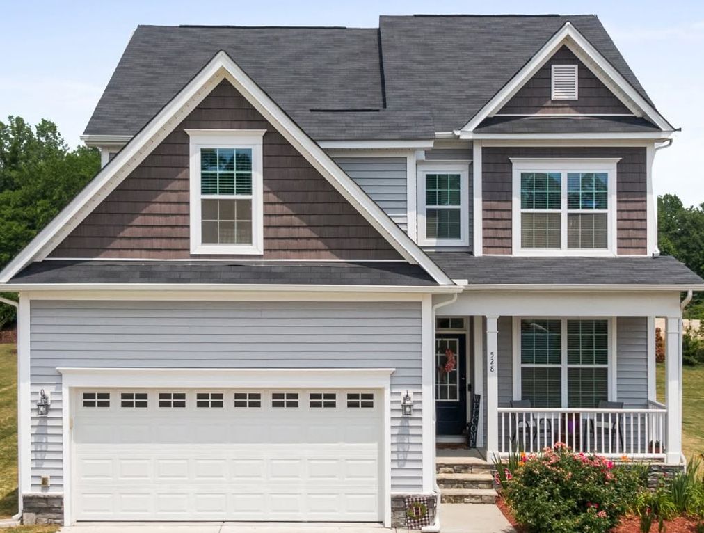 Two-story gray suburban house with white trim, attached garage, and front porch