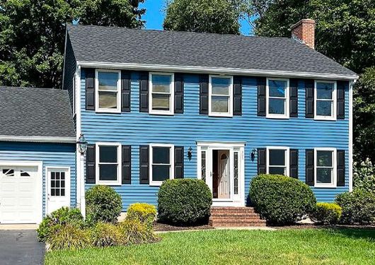Blue two-story suburban house with white trim, black shutters, and a garage, seen from the front.