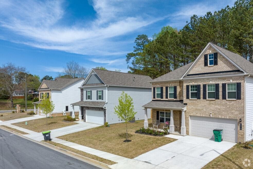 Suburban street with two single-family houses, driveways, and a blue sky.