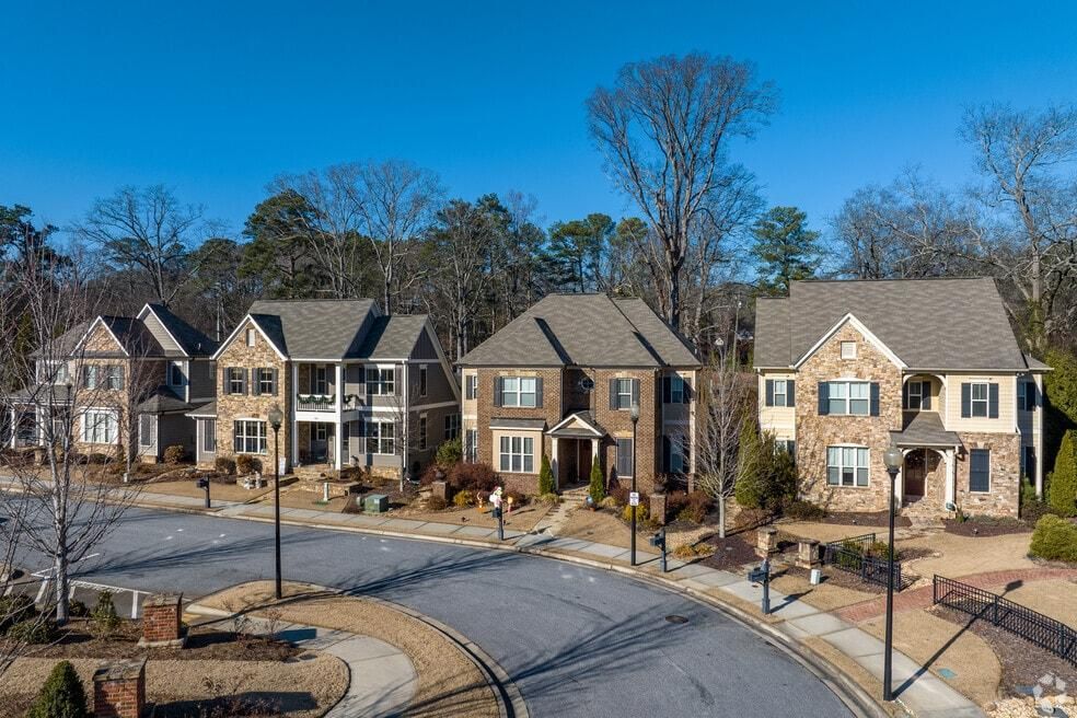 Row of modern townhouses along a curving street on a clear blue-sky day