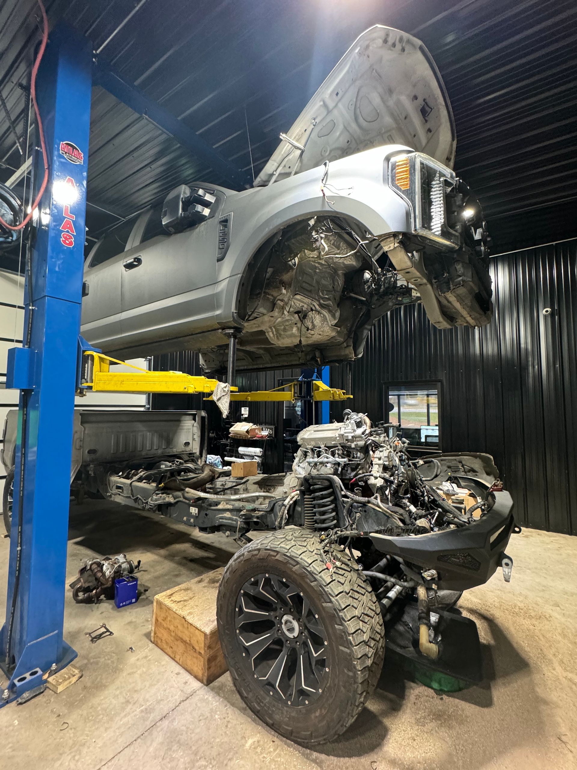 Truck lifted on a blue hydraulic lift in a repair shop. | Pro Import Automotive Service and Repair