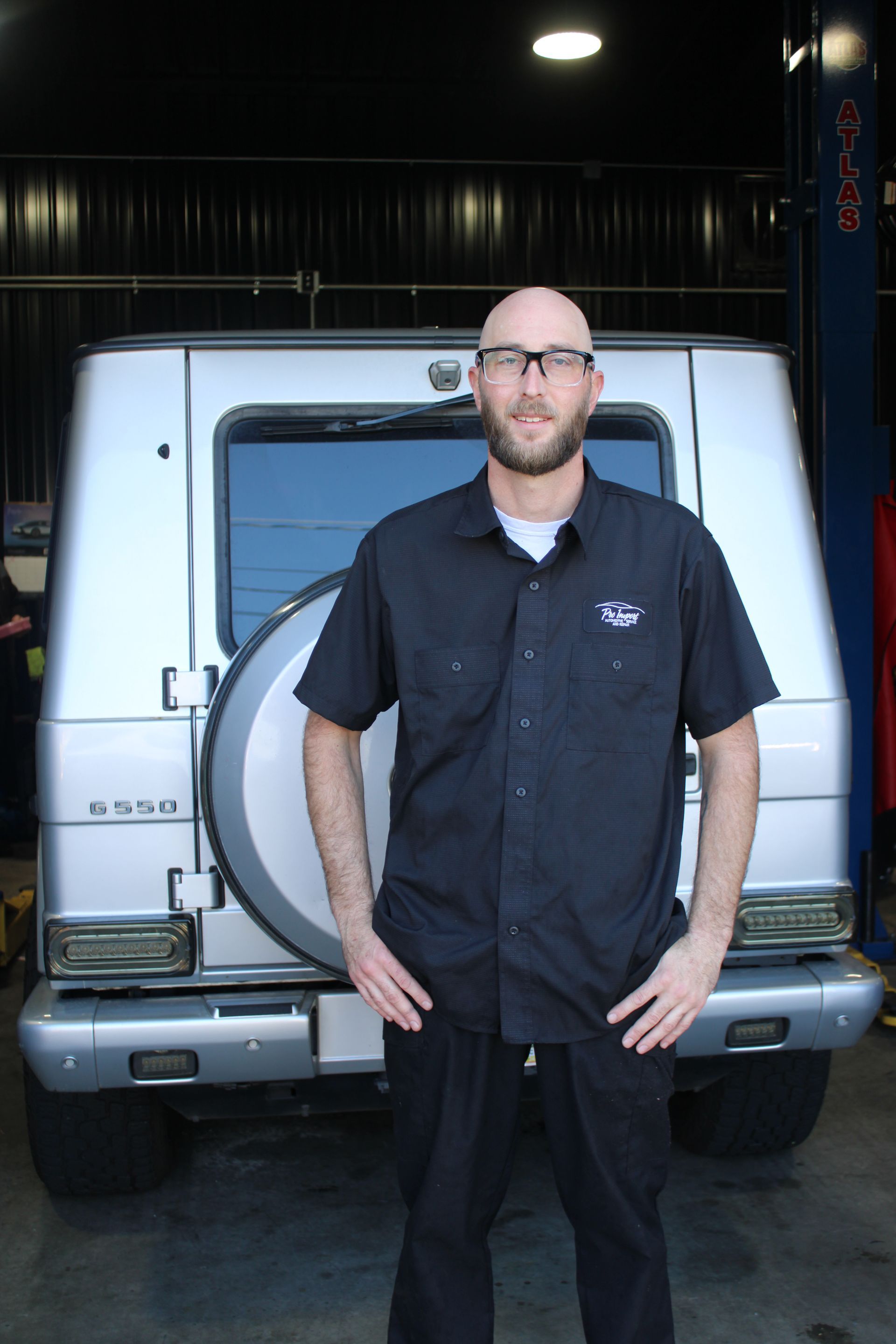 A person wearing glasses and a black uniform shirt. | Pro Import Automotive Service and Repair