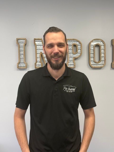 A person with a beard and short hair, smiles while standing outdoors. | Pro Import Automotive Service and Repair