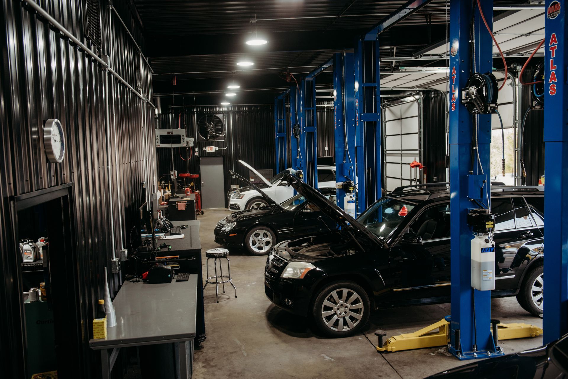 Auto repair shop with several cars on lifts and tools in a dimly lit garage | Pro Import Automotive Service and Repair