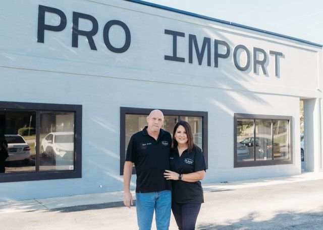 Two people standing outside a storefront labeled “PRO IMPORT” | Pro Import Automotive Service and Repair