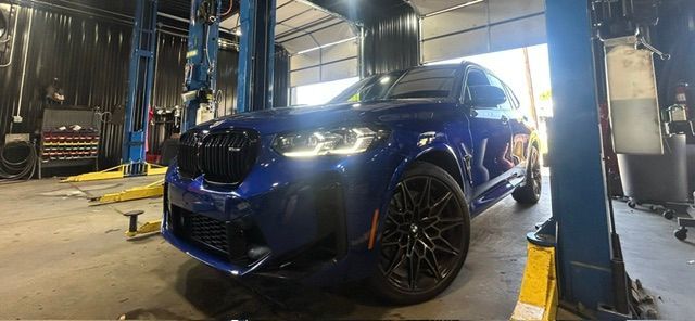 Blue SUV in an auto shop, parked on a lift under bright lights | Pro Import Automotive Service and Repair