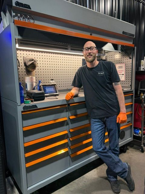 Man standing beside a gray and orange tool cabinet in a workshop. | Pro Import Automotive Service and Repair