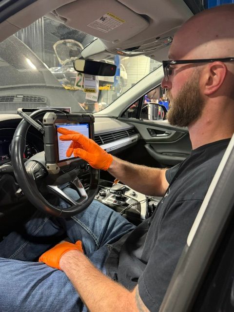 Man in orange gloves inspecting a car interior | Pro Import Automotive Service and Repair