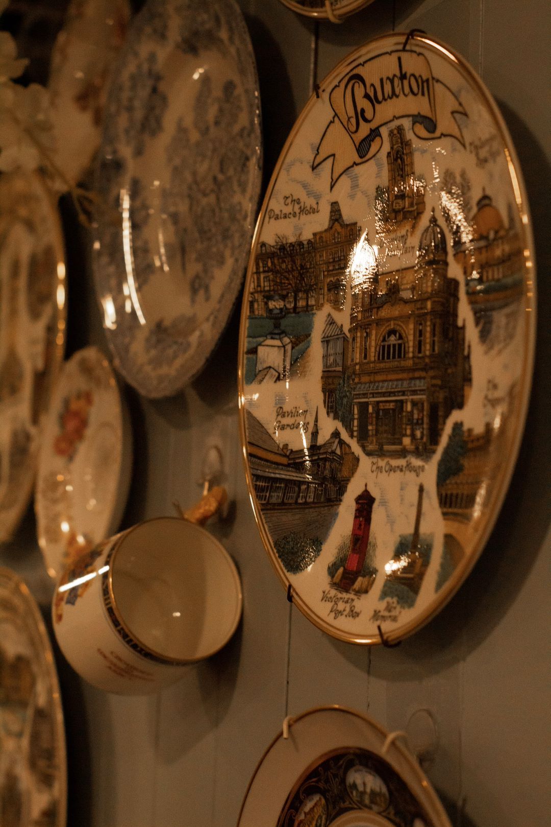 Collection of decorative plates and a cup hanging on a wall, one plate with 
