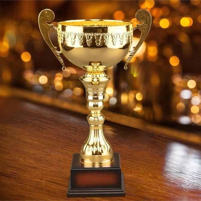 A Gold Trophy is Sitting on a Wooden Table  — Jimani Trophies & Engraving In Dapto, NSW