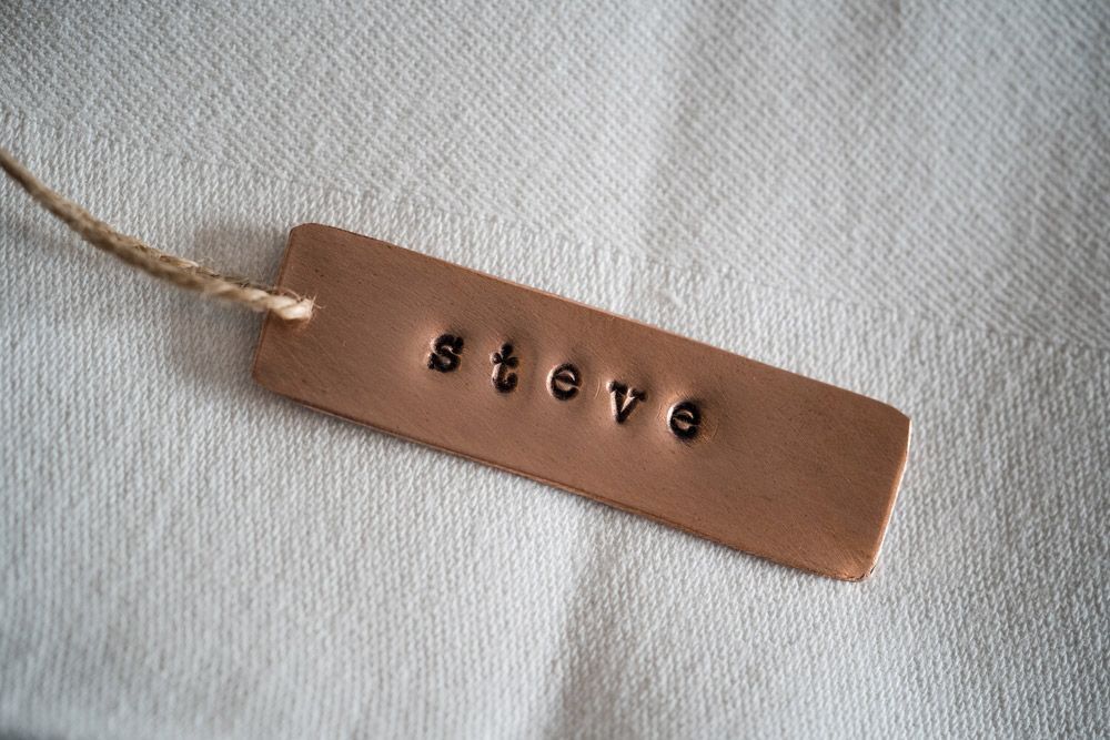 A Brown Tag with The Name Steve Written on It Is Sitting on A White Cloth  — Jimani Trophies & Engraving in Dapto, NSW
