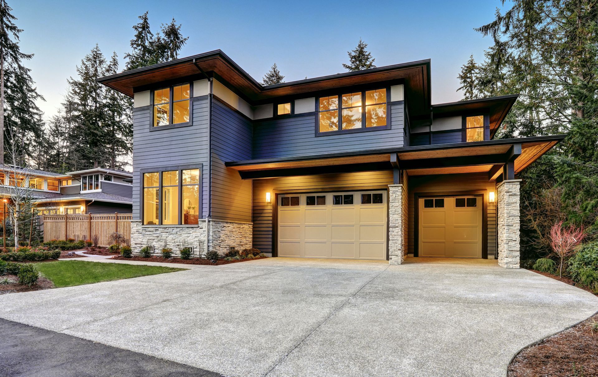Une grande maison bleue avec deux portes de garage et une allée.