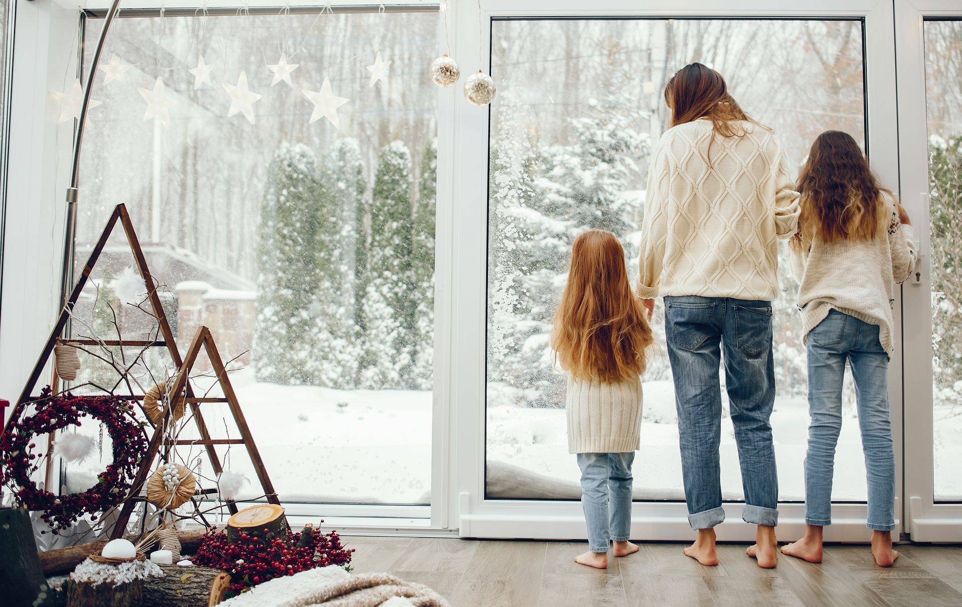Une mère et ses deux filles regardent la neige par la fenêtre.