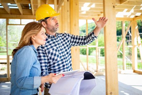 Un homme et une femme regardent un plan sur un chantier de construction.