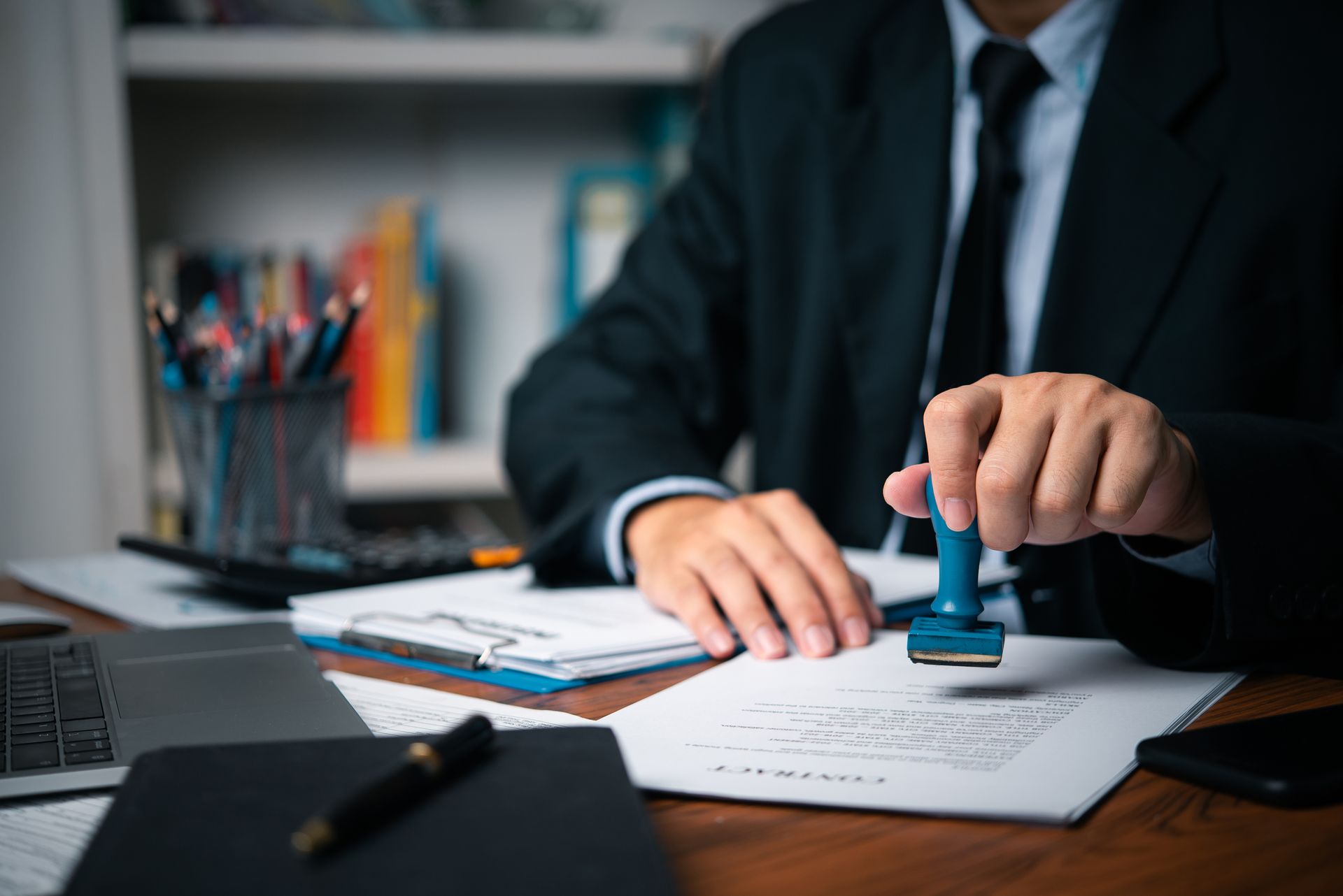 Un homme en costume et cravate tamponne un document.