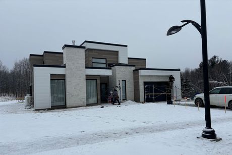 Une grande maison est assise dans la neige à côté d'un lampadaire.