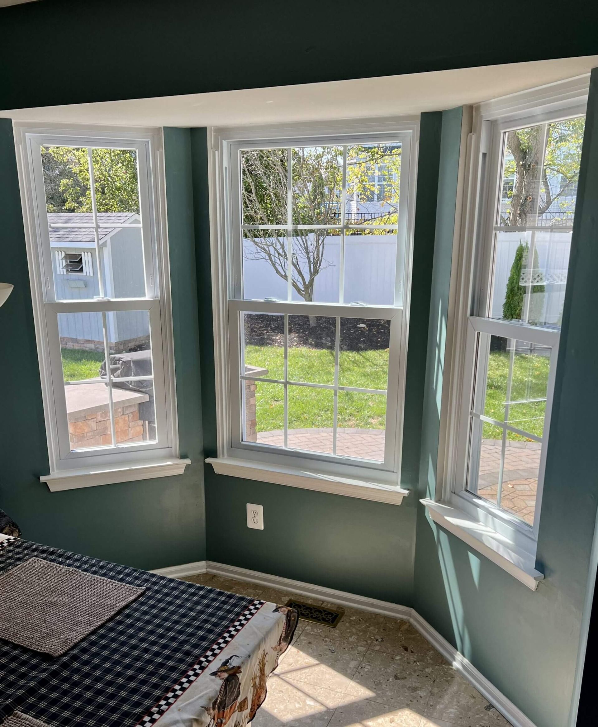 Small bay window nook with green walls, white trim, and a bench by bright windows.