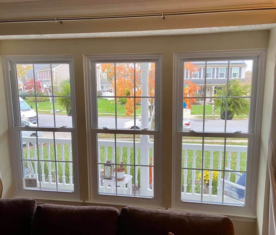 Living room bay window overlooking a quiet suburban street and front porch with white railing