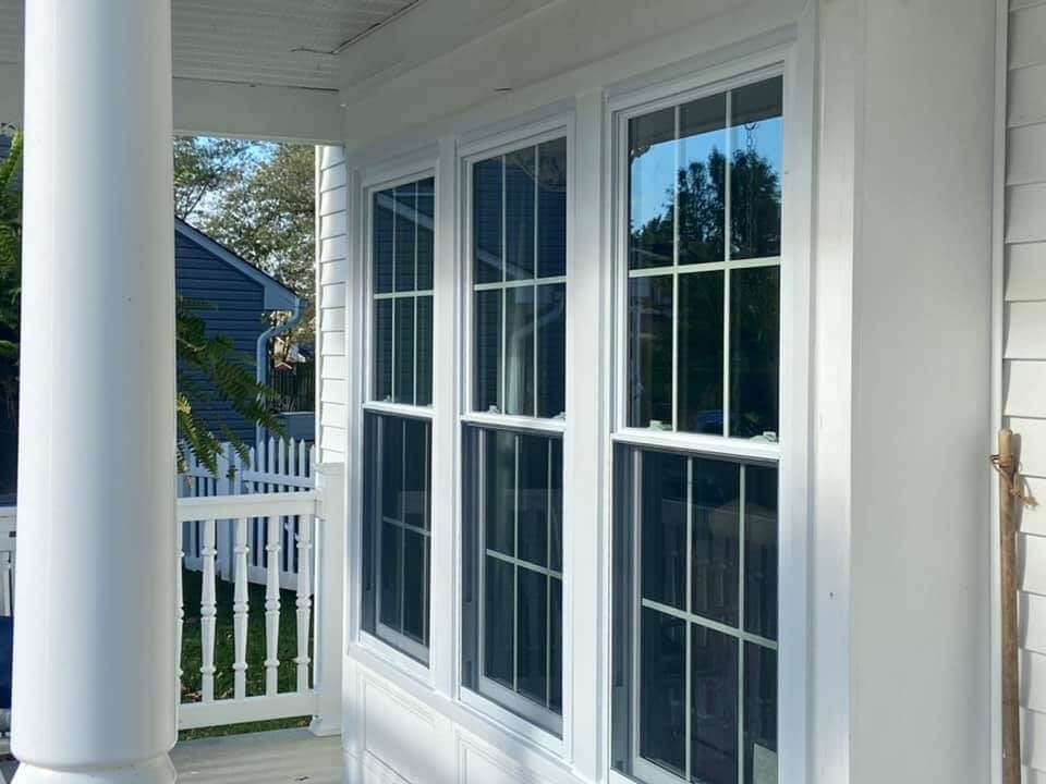 White porch with French doors, white columns, and a view of a fenced yard outside