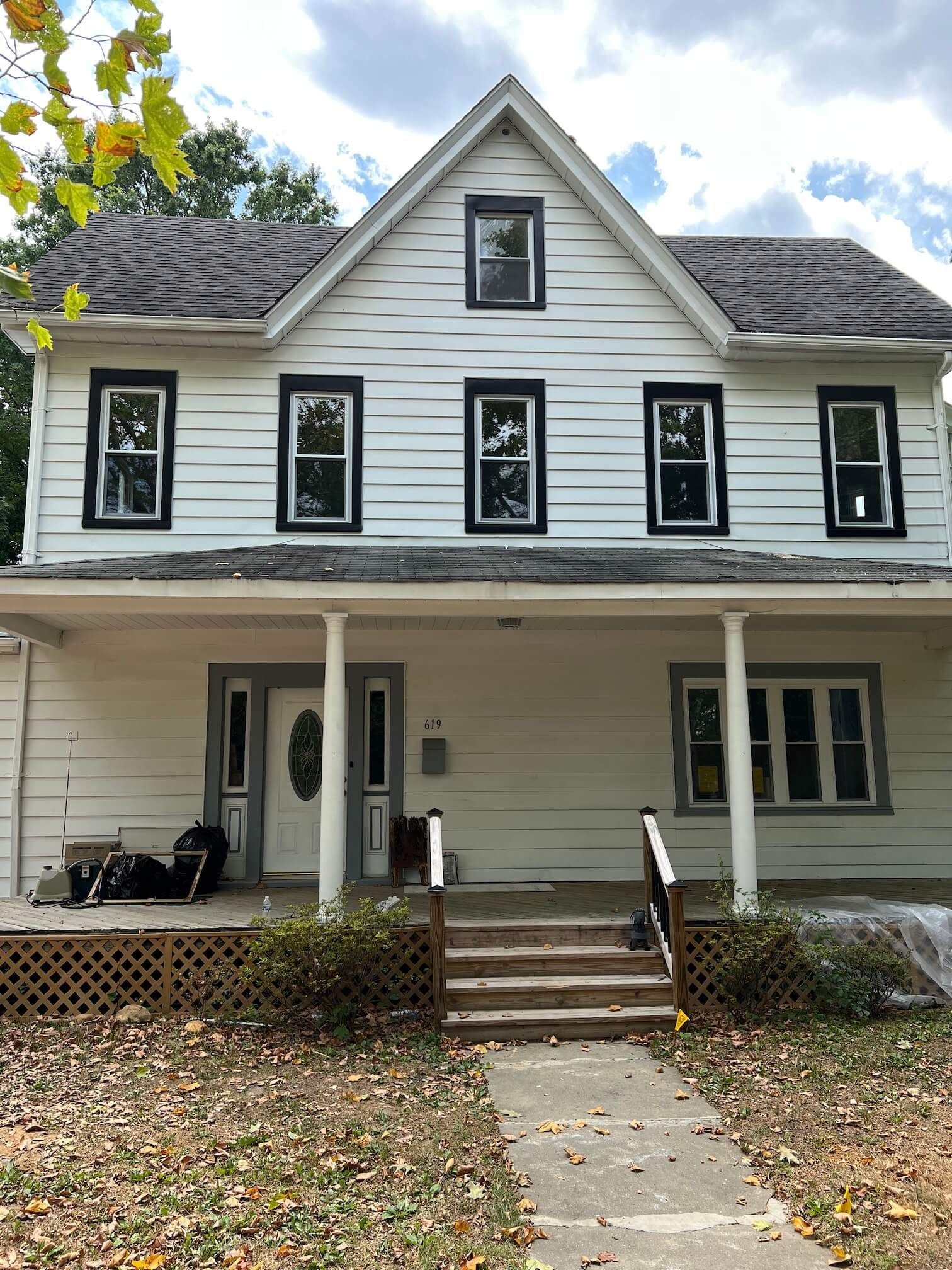 Two-story white house with black-trimmed windows, front porch, and steps leading to the entrance.