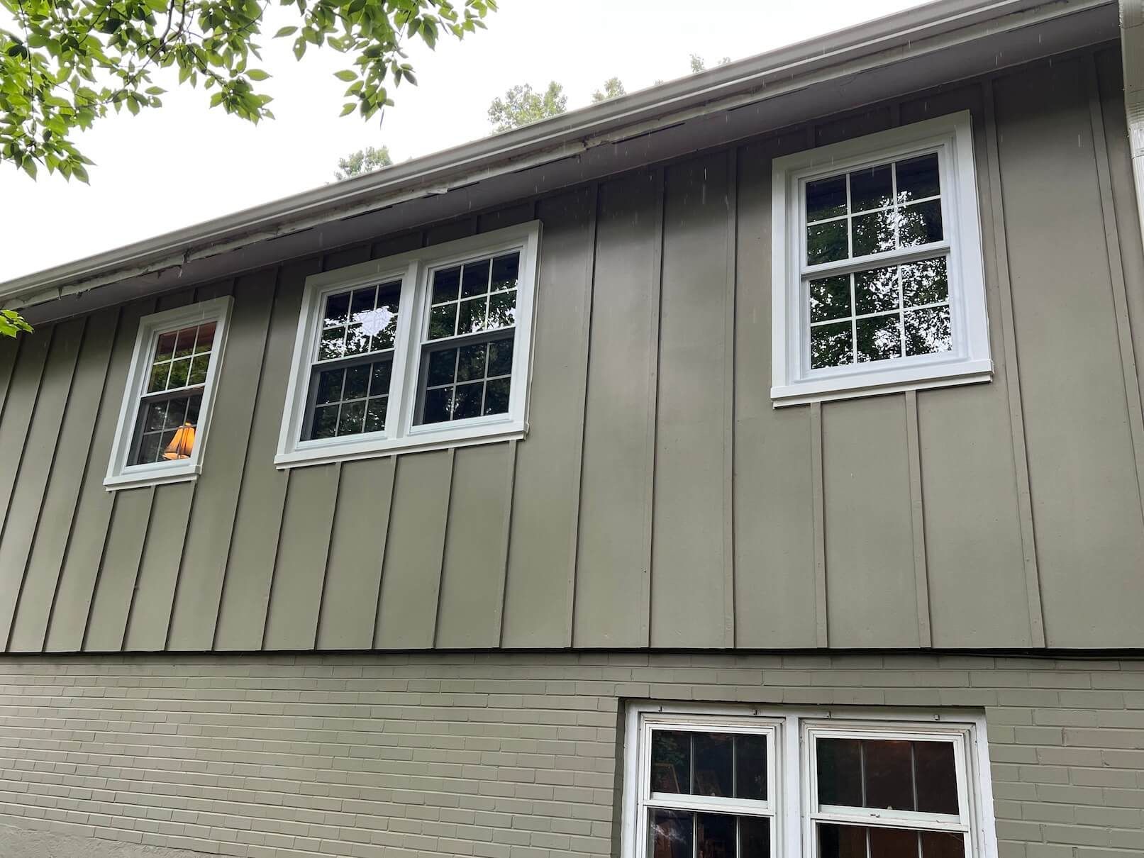Two-story house exterior with gray siding and several white-trimmed windows