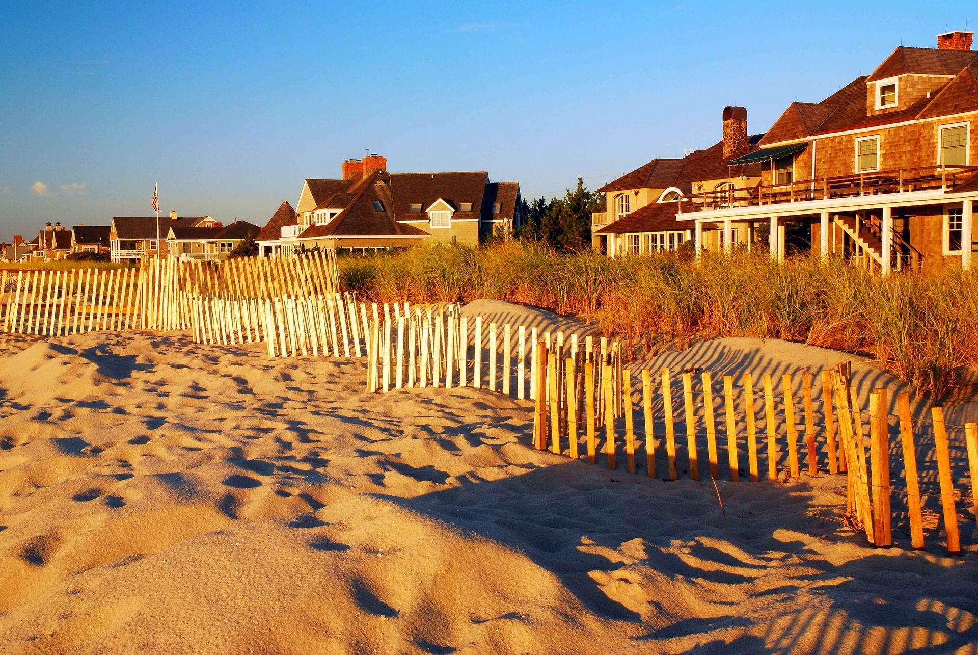 Sandy beach with wooden fence and beachfront houses at sunset
