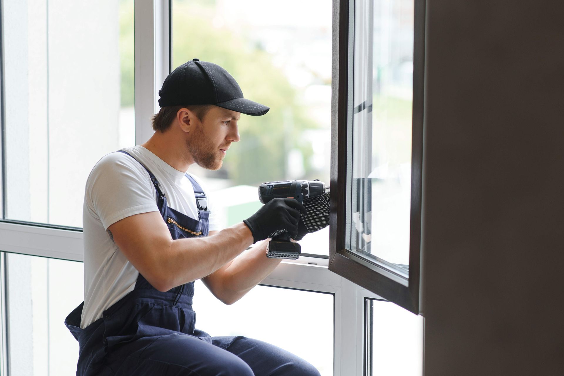 Technician wearing gloves inspects a window frame indoors.