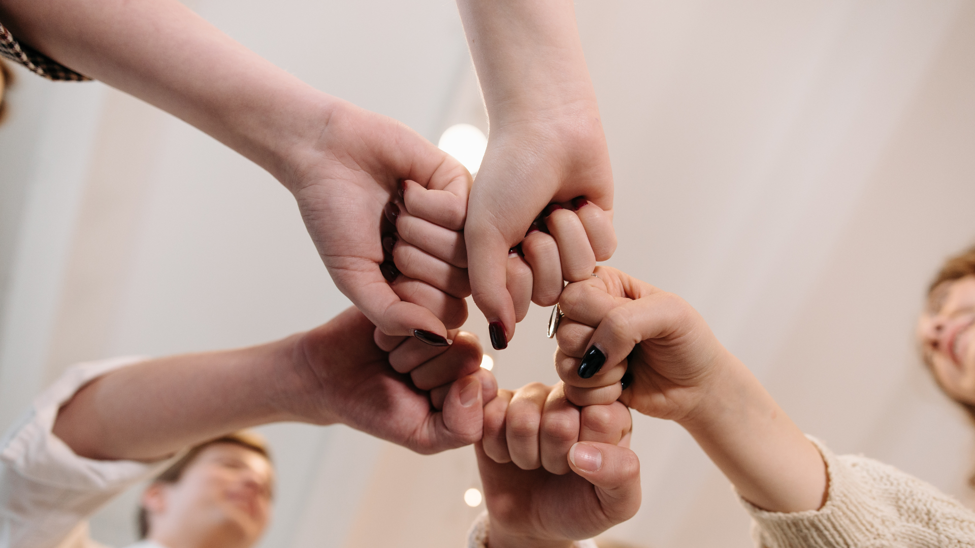 A group of people are putting their hands together in a circle.