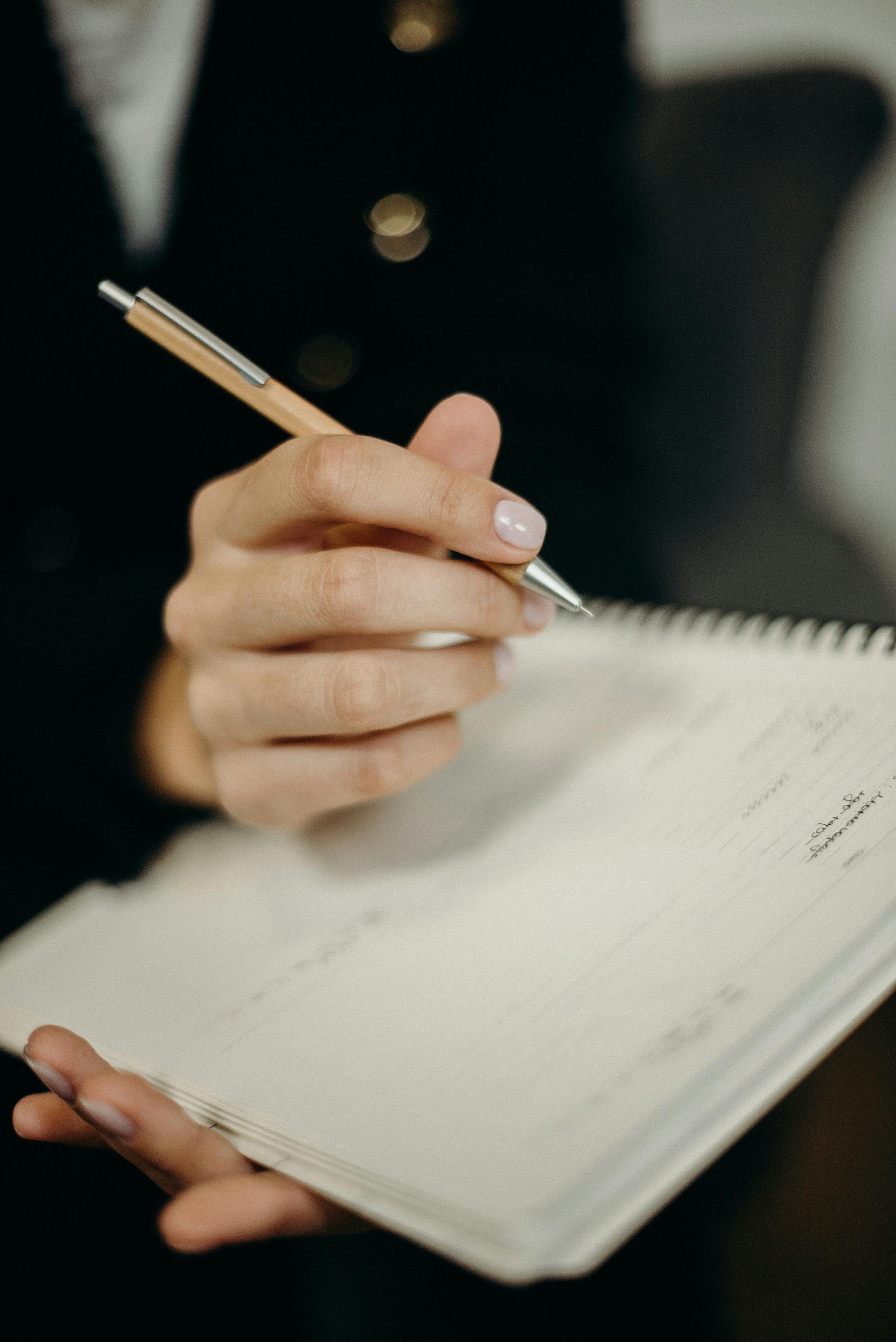 Pesssoa escrevendo em um caderno com caneta