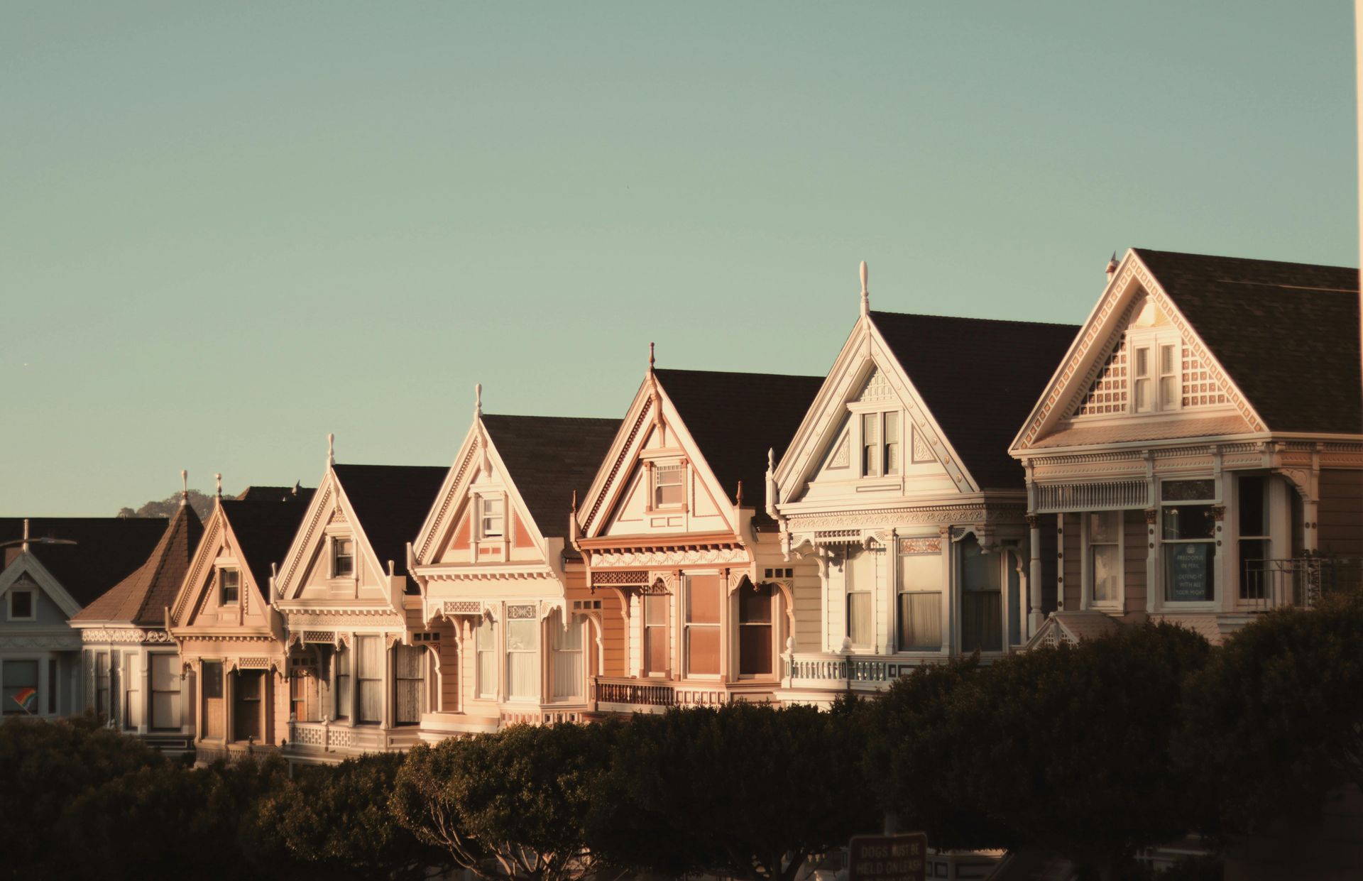 Row of Victorian houses with colorful facades against a clear sky.