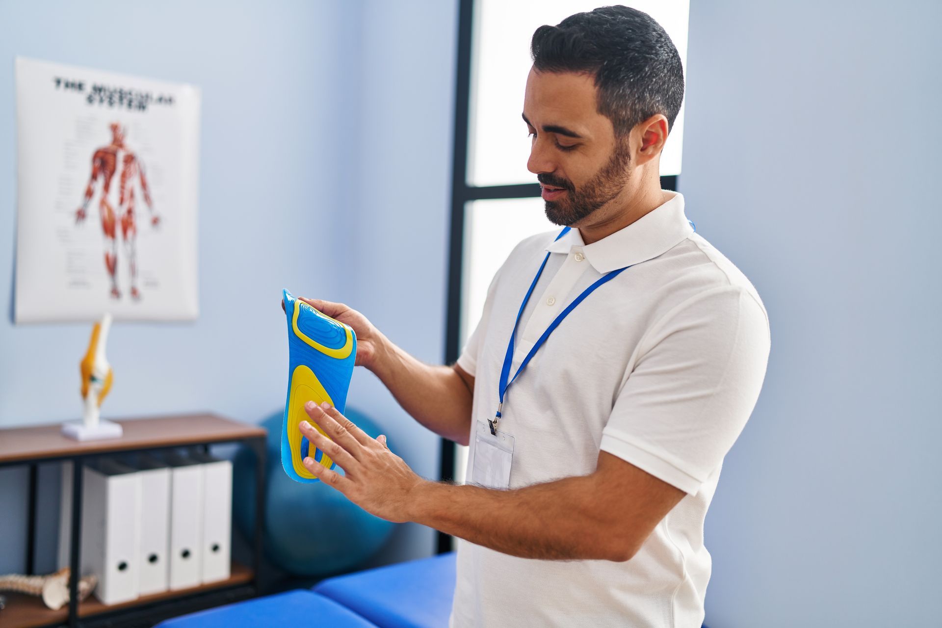 Man holds a shoe insole while working at a podiatry center.