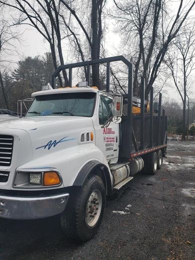 White dump truck parked on a wet road in a wooded area